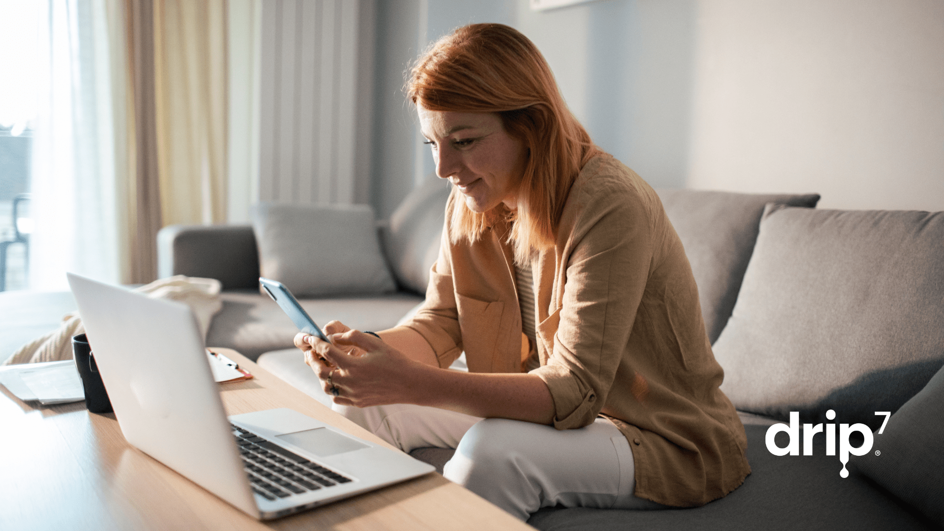 Women has a laptop open and is typing on her cell phone, she's taking a break to complete her company's cybersecurity training