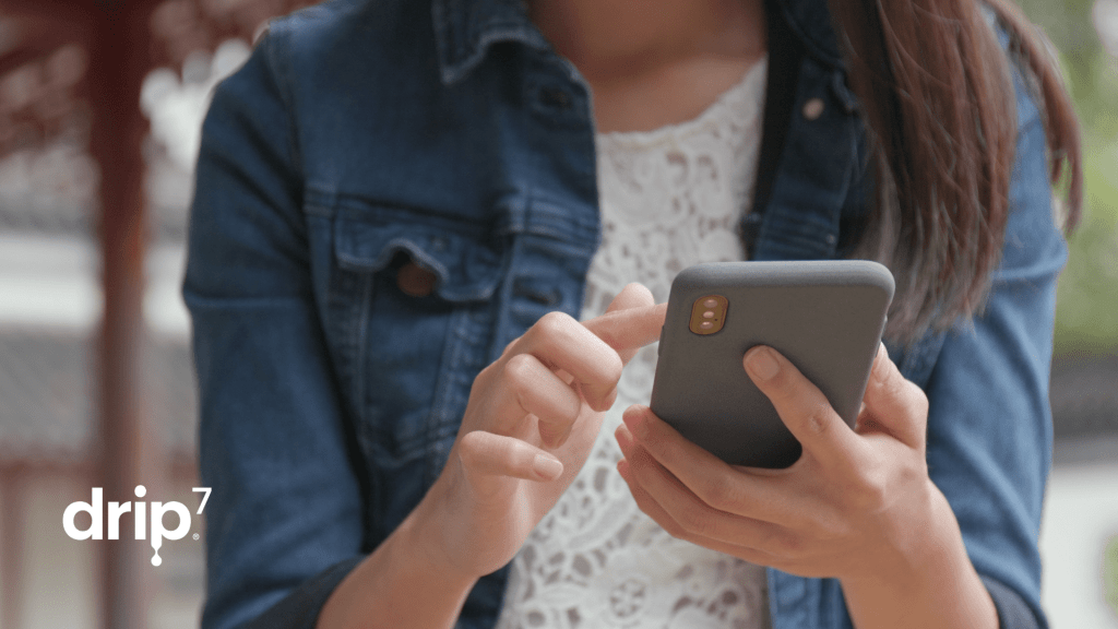Woman types on a phone while outside, working on her company's mandated cybersecurity employee training